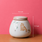 Keramische asurn voor katten en kleine huisdieren op houten tafel met roze achtergrond